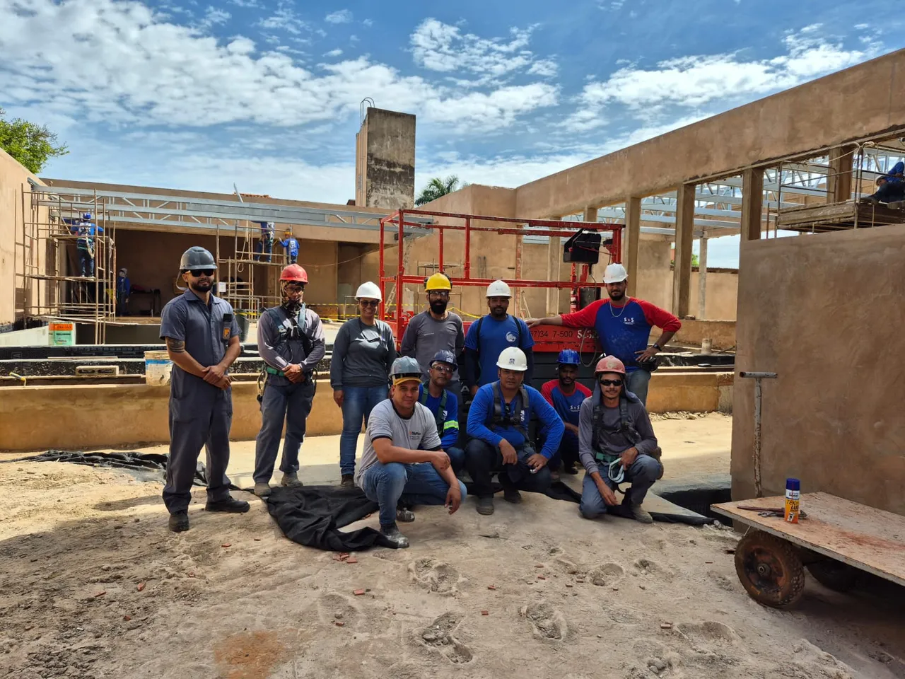 Turma in company em obra com plataforma tesoura